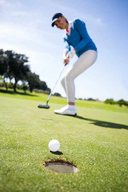 Женский гольфист, ставящий мяч