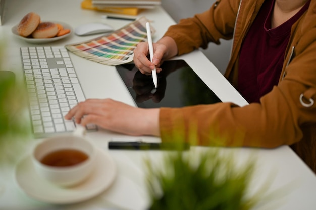 Фото Женщина-графический дизайнер занята работой за своим офисным столом с помощью цифрового графического планшета и компьютера