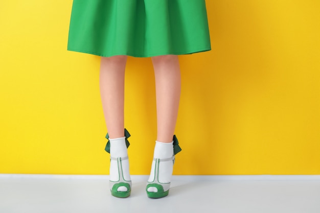 Женские ножки в зеленых туфлях на высоком каблуке и носках на цвете