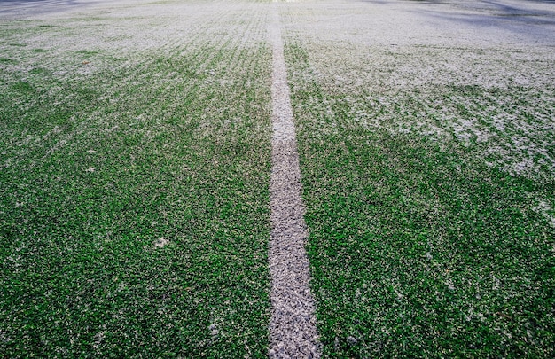 Photo the football field with artificial green grass is covered with a light layer of snow