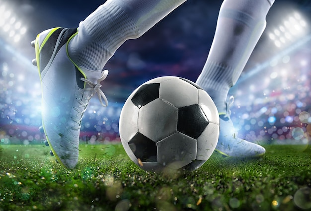 Футбольная сцена в ночном матче с крупным планом футбольной обуви, бьющей по мячу с силой.