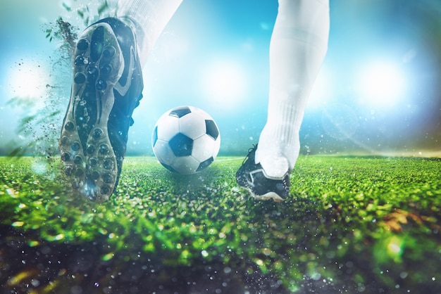 Футбольная сцена в ночном матче с крупным планом футбольной обуви, ударяющей по мячу