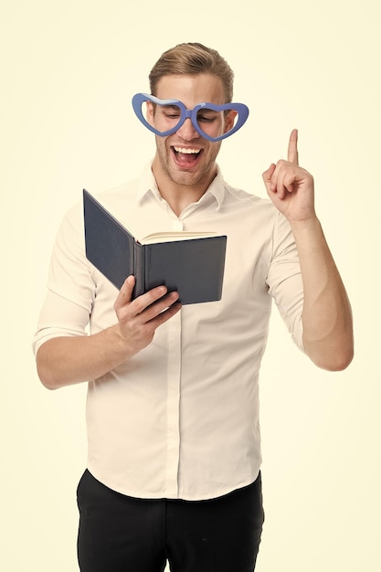 Фото Найден ответ мужчина красивый молодой, указывающий вверх и смеющийся мужчина счастливое лицо в очках в форме сердца читает книгу парень нашел ответ в книге изолированный белый фон хорошая идея