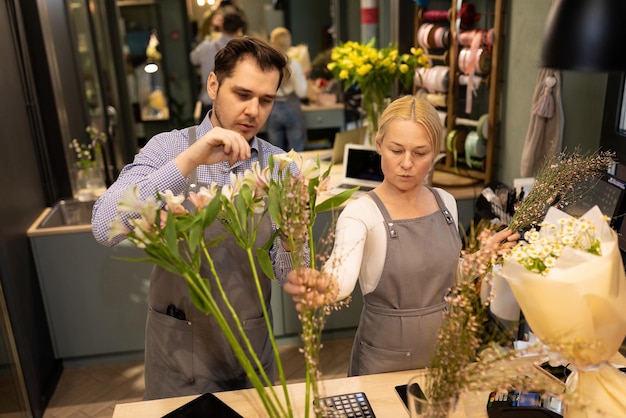 Флорист и его помощник заботятся о свежих цветах в магазине букетов