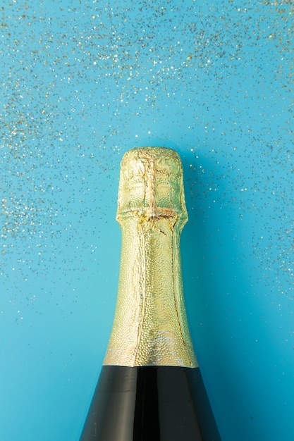 Фото Плоский праздник празднования, бутылка шампанского на синем фоне с блеском.
