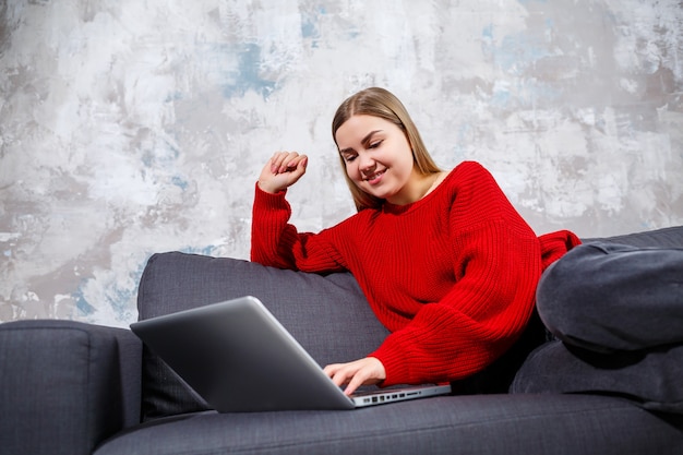 Фото Женщина-фрилансер сидит на диване в уютном домашнем интерьере и работает удаленно на современном портативном компьютере, опытная женщина смотрит онлайн-вебинар на веб-сайте. работа из дома во время карантина