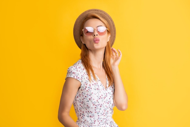 Фото Забавная молодая женщина в соломенной шляпе и солнцезащитных очках на желтом фоне