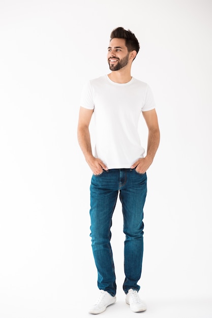 Photo full length portrait of an attractive young bearded man wearing casual clothing standing isolated over white wall, looking away