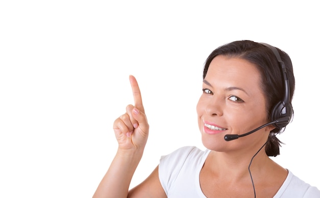 Gelukkige vrouw met headset werken bij callcenter toont vinger richting naar Copyspace voor jou ontwerp op een witte achtergrond