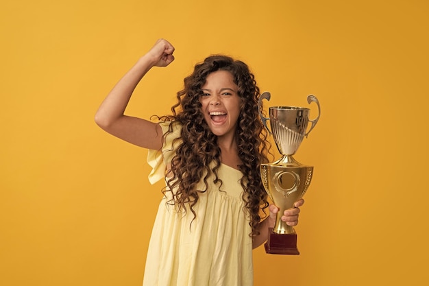 Foto gelukkig tienermeisje houdt gouden bekerprestatieprijs om succes en overwinning te vieren
