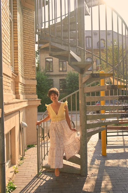 девушка с короткой стрижкой в желтом платье на солнечной спиральной лестнице в Копенгагене