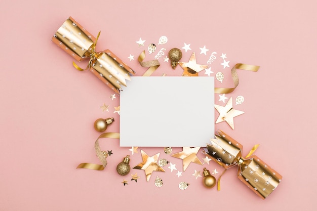 Золотой рождественский крекер с пустой белой этикеткой роскошный золотой праздничный крекер на пастельно-розовом фоне