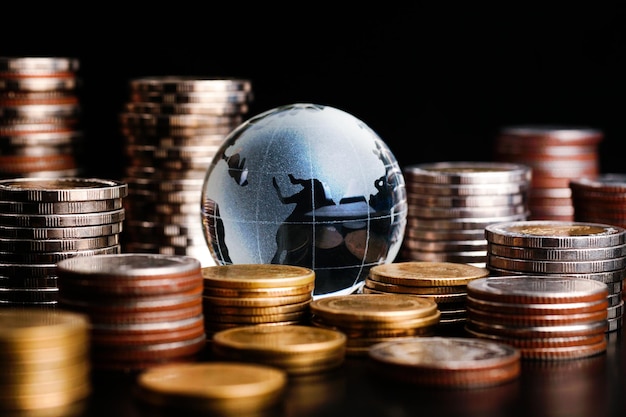 Глобус и стек с монетами. Деньги заставляют мир вращаться, концепция мировых денег.