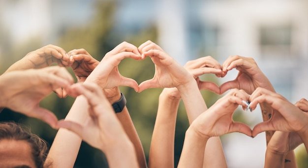 Photo hand heart and love with a group of people making a sign with their hands outdoor together in the day crowd freedom and community with man and woman friends doing a gesture to promote health