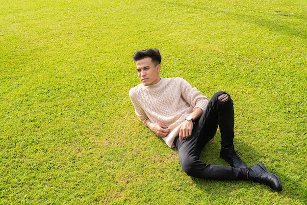 Красивый молодой человек, лежащий на траве летом в парке