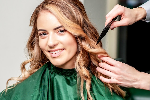 Photo hands of hairdresser combs hair of smiling woman in hair salon