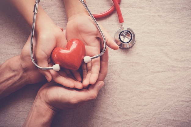 hands holding red heart with stethoscope, heart health, health insurance concept 