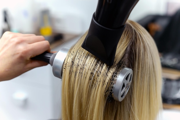 Фото Парикмахер сушит волосы феном женщина в салоне. close-up.концепция красоты и моды