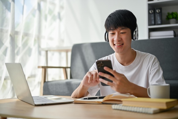 Счастливый молодой азиат слушает музыку через наушники в гостиной