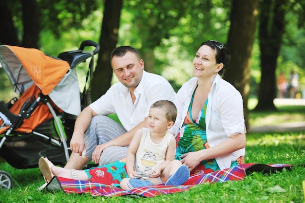 Счастливая молодая семья в парке отдыхает и развлекается с беременной женщиной