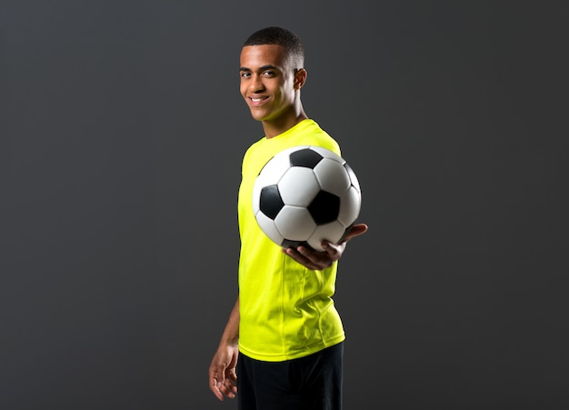 Фото Счастливый футболист человек с темнокожие игры, ловя мяч с руки на темном фоне