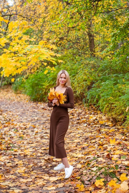 Фото Счастливая улыбающаяся женщина, держащая в руках желтые кленовые листья