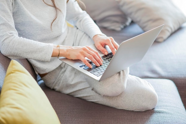 Фото Высокоугольный вид женщины, использующей ноутбук, сидящей на диване дома