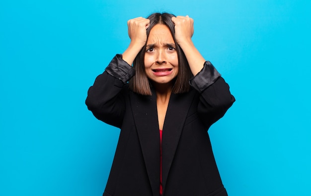 Photo hispanic woman feeling stressed and anxious, depressed and frustrated with a headache, raising both hands to head