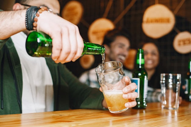 Foto amici indiani in un pub. ragazzi e ragazza al bar. celebrazione davanti a un boccale di birra.