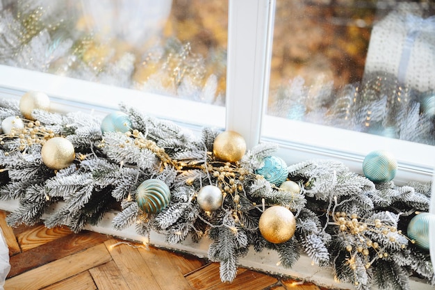 Kerstcompositie Besneeuwde kerstboomslinger met blauwgouden snuisterijspeelgoed en slinger