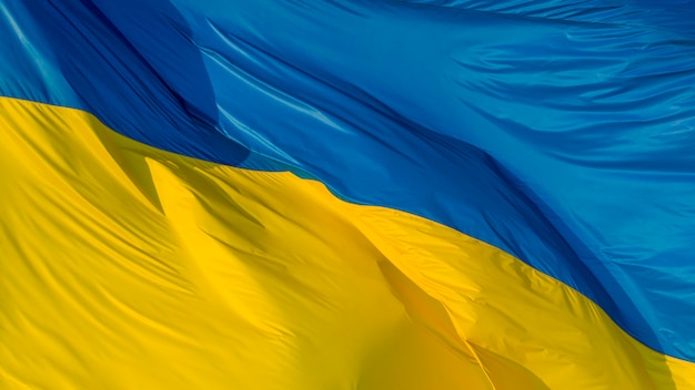 Large Ukrainian flag, made of high quality material, flutters in the wind, creating waves.