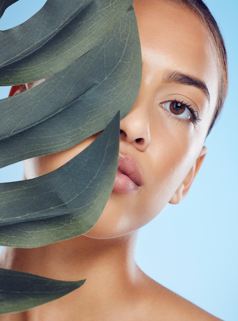 Photo leaf beauty and portrait of a woman in a studio with a skincare natural and facial treatment health wellness and female model from brazil with a plant for organic face routine by blue background