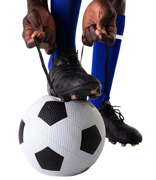 Photo low section of african american male soccer player tying shoelace on ball against white background