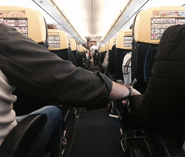 Photo low section of friends holding hands in airplane