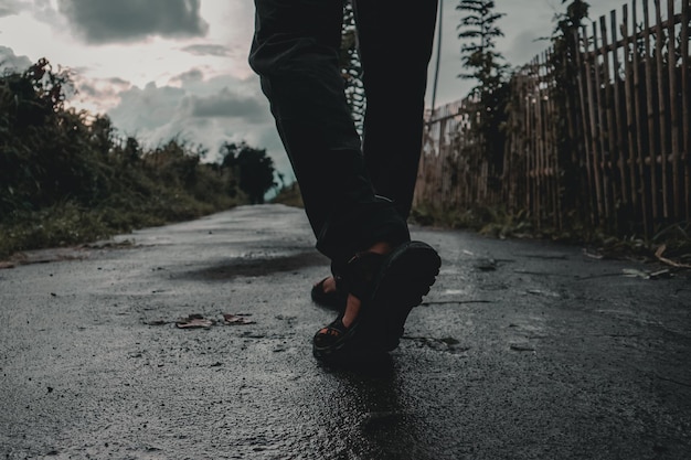 Photo low section of man standing on road after rain and twilight comes