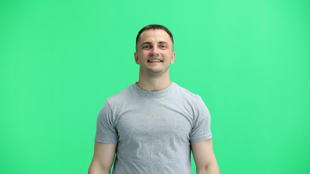 Photo a man in a gray tshirt on a green background closeup