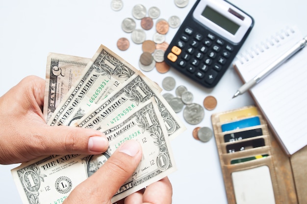 Руки человека с банкнотами с монетами и кредитной картой в кошельке на столе