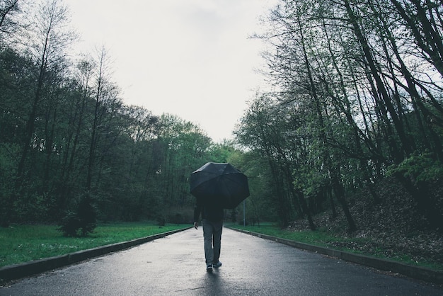 Photo man walks by park on rainy day