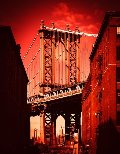 Photo manhattan bridge with the empire state building and brick wall buildings viewed from dumbo, brooklyn, new york