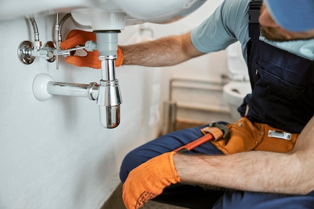 Photo male plumber hands repairing pipe under sink