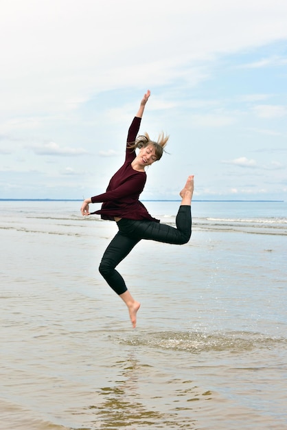 사진 하늘에 대항하여 해변에 점프 중 성인 여성