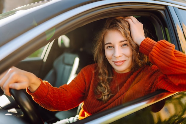Молодая улыбающаяся женщина за рулем машины едет по городу Концепция стиля жизни
