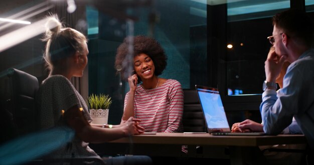 Foto multi-etnisch startend zakelijk team over ontmoeting in moderne nachtelijke kantoorinterieur brainstormen, werkend op laptop