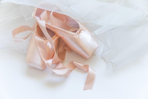 Фото Новые пастельно-бежевые балетные туфли с атласной лентой и юбкой тутут на белом фоне