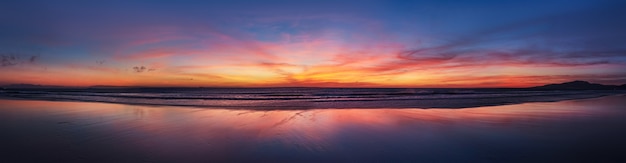 Панорама пляжа океана захода солнца города Испании Тарифа Андалусии. Атлантический океан волны фон яркий волшебный закат небо