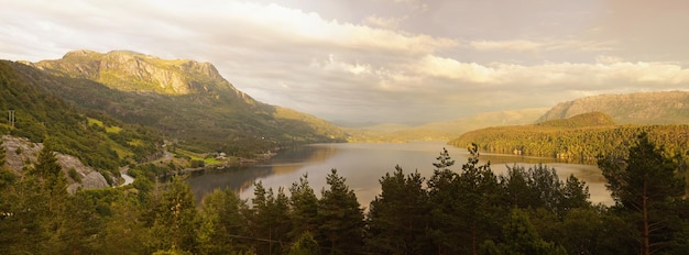 Фото Панорамный вид на озеро среди деревьев на фоне облачного неба