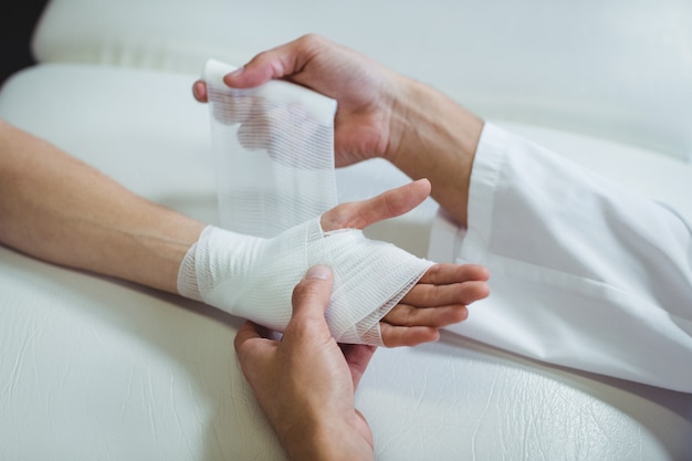 Фото Физиотерапевт накладывает повязку на поврежденную руку пациента
