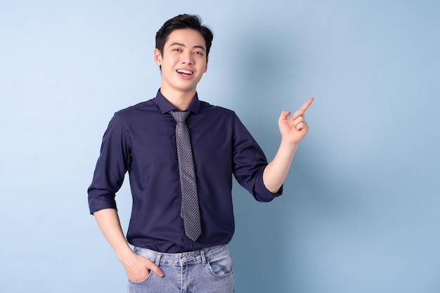 Photo portrait of young asian businessman posing on blue background