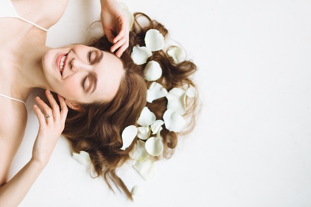 Photo portrait of beautiful young woman with white rose petal on white background. relax and spa