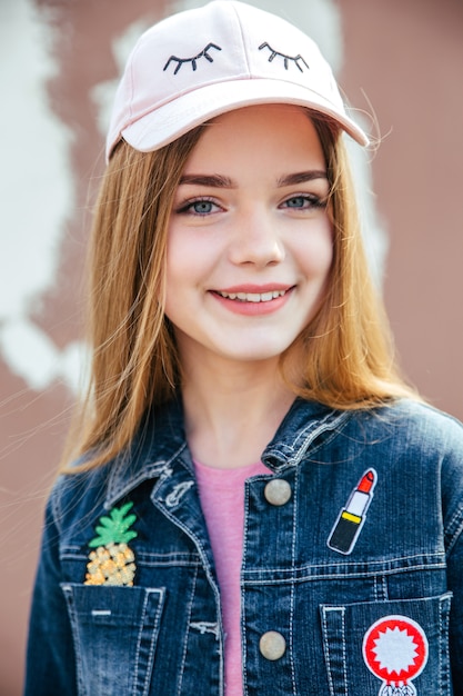 Photo portrait closeup beautiful young girl in city. smiling girl in hat